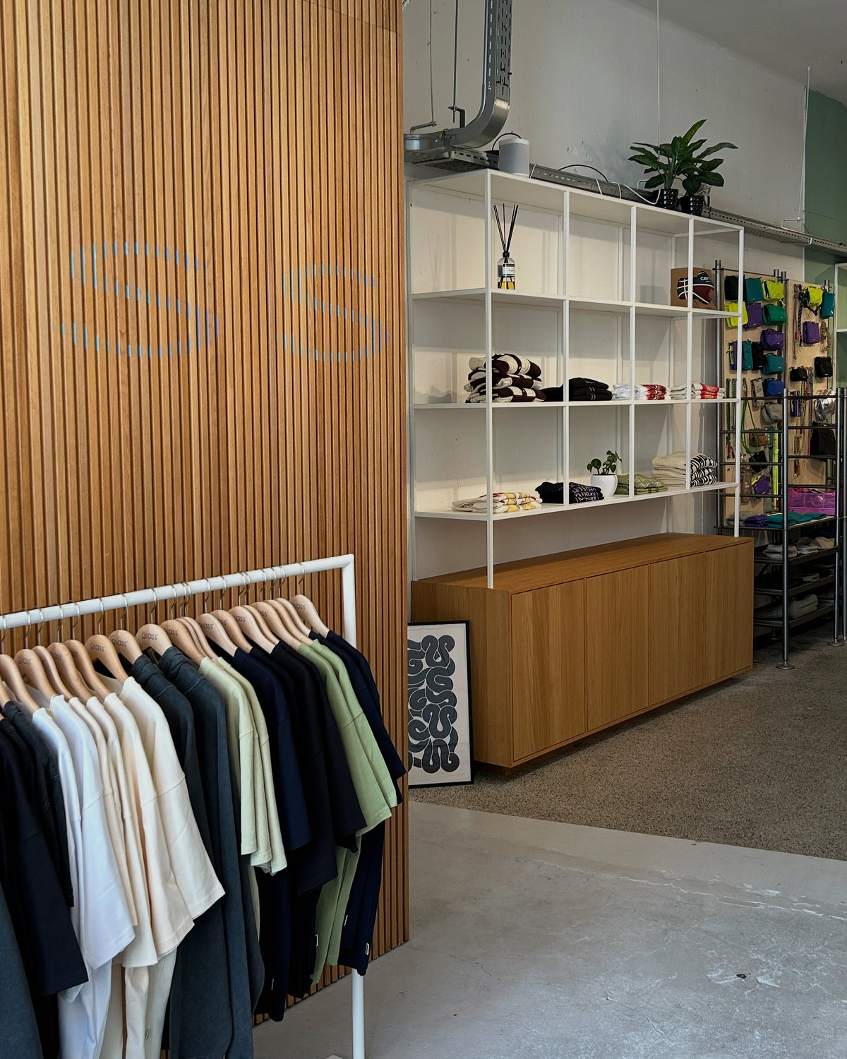 Interieur van Glass Store met hout, staal en beton en kledingrekken met streetwear